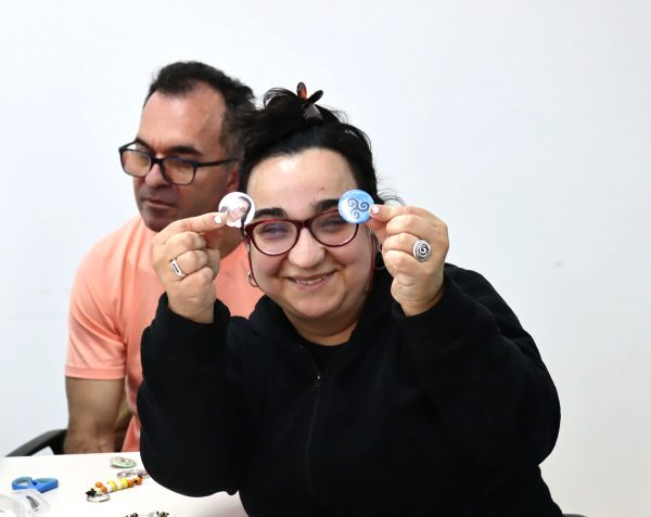 Foto del taller de manualidades, arde lucus, del programa de Atención a Personas con Discapacidad. Participante nos enseña las chapas que han hecho.