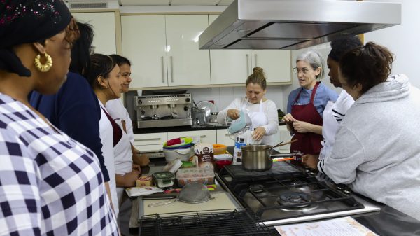 Foto del taller de repostería del segundo ciclo de salud integral de las mujeres donde las participantes atienden a las explicaciones de la profesora