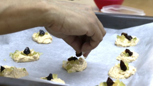 Foto del taller de repostería del segundo ciclo de salud integral de las mujeres donde una participante añade toppins a las galletas